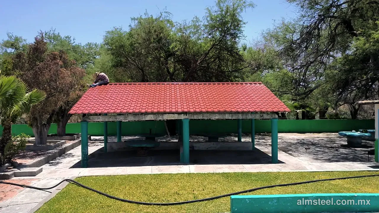 Palapa con teja española roja sobre columnas, junto a un jardín